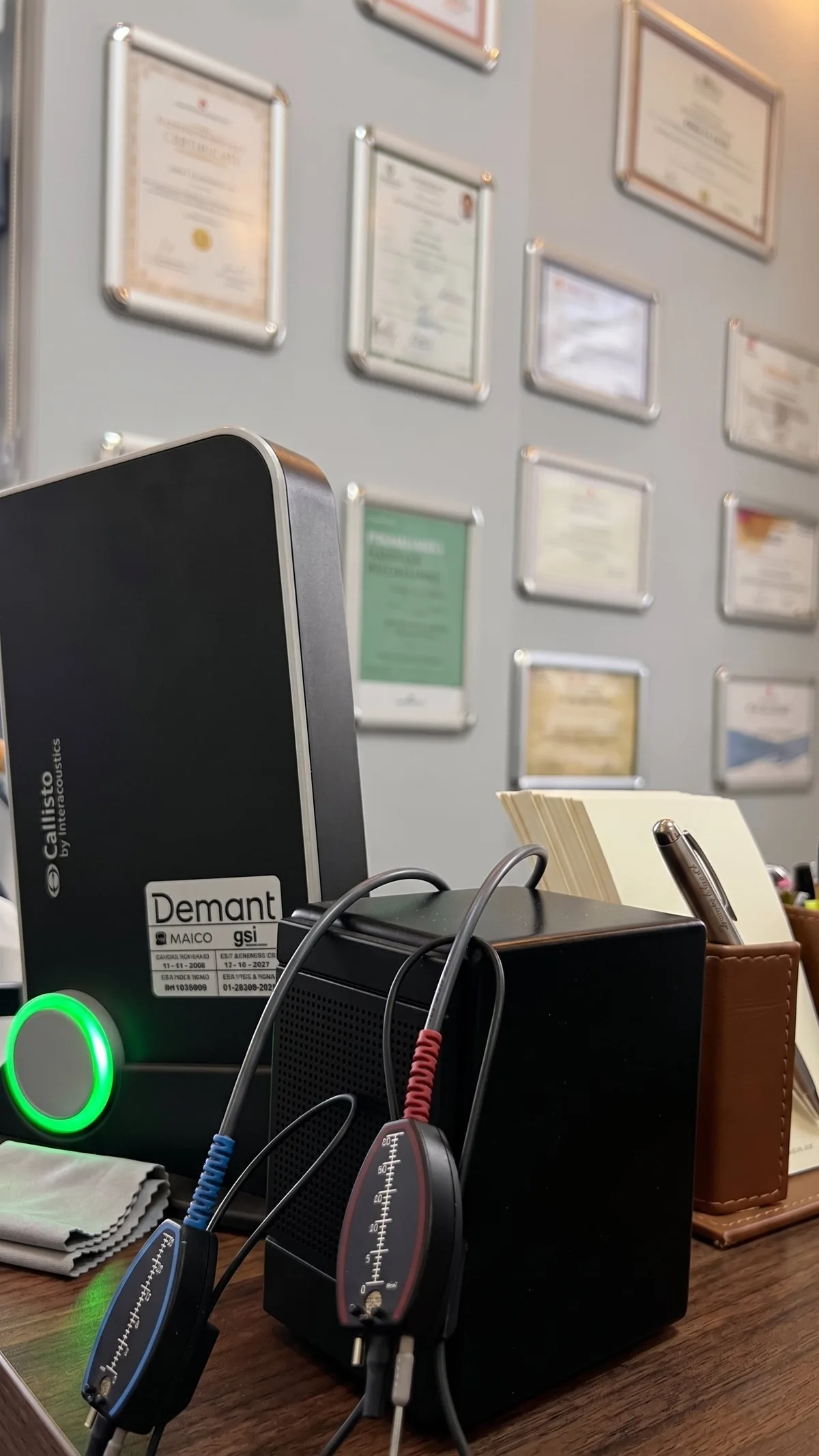 Çankaya İşitme Cihazı Merkezi'nde Interacoustics Callisto REM ölçüm cihazı — yapım aşamasında, mavi ve kırmızı prob mikrofonlar görünüyor, arka planda merkez sertifikalar
